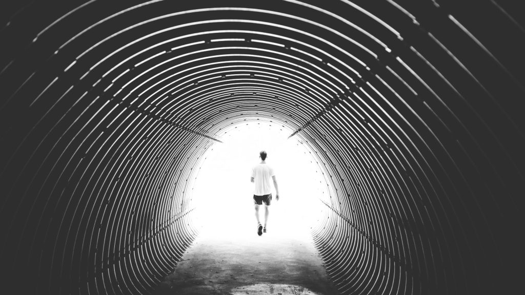 Man Walking Through Light At The End Of The Tunnel